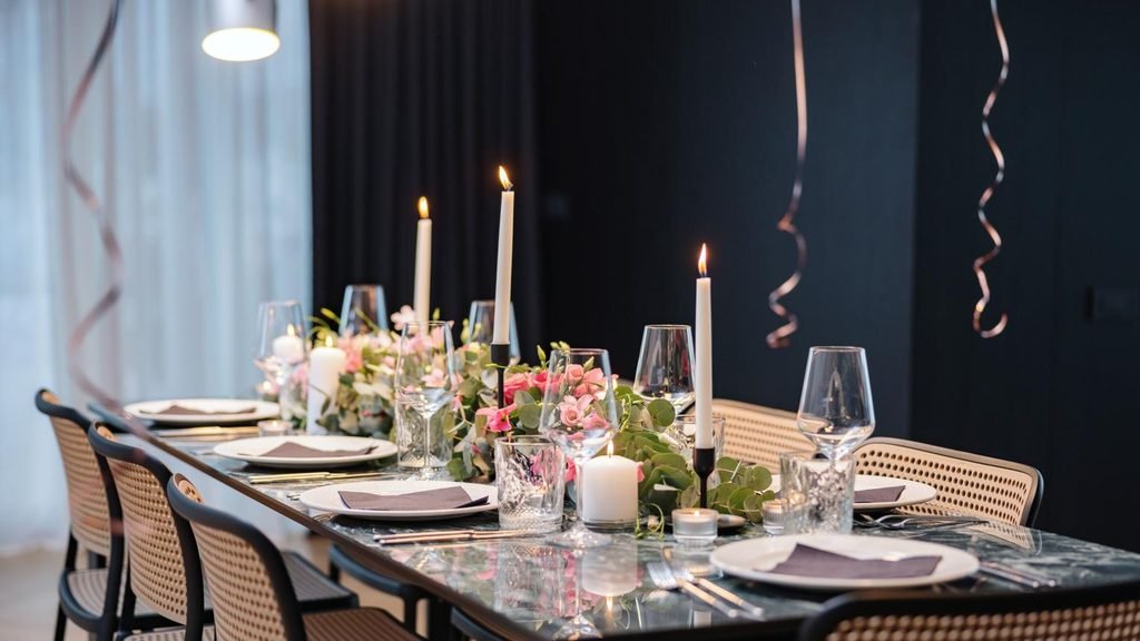 Elegant small celebration featuring a beautifully decorated cake, fresh flowers, candles and warm ambient lighting.